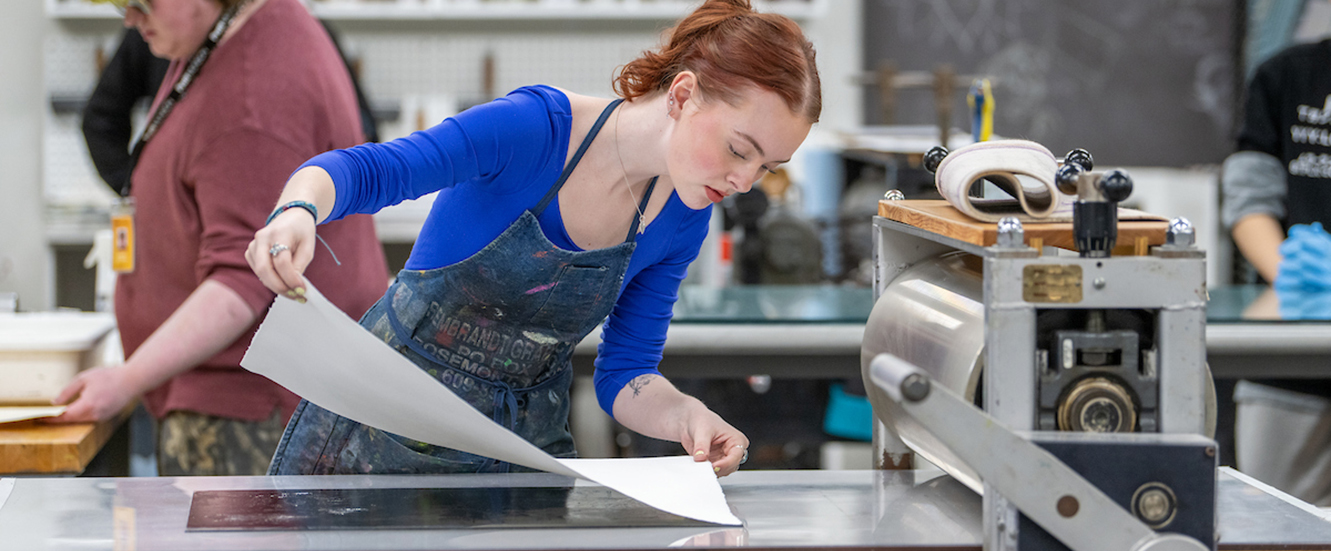 girl laying paper down on printmaking table
