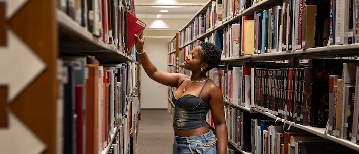 Student in library taking book of shelf