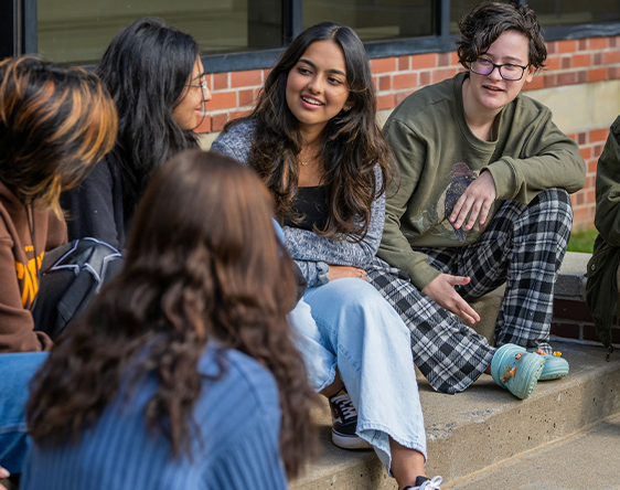 students sitting in front of the studio building
